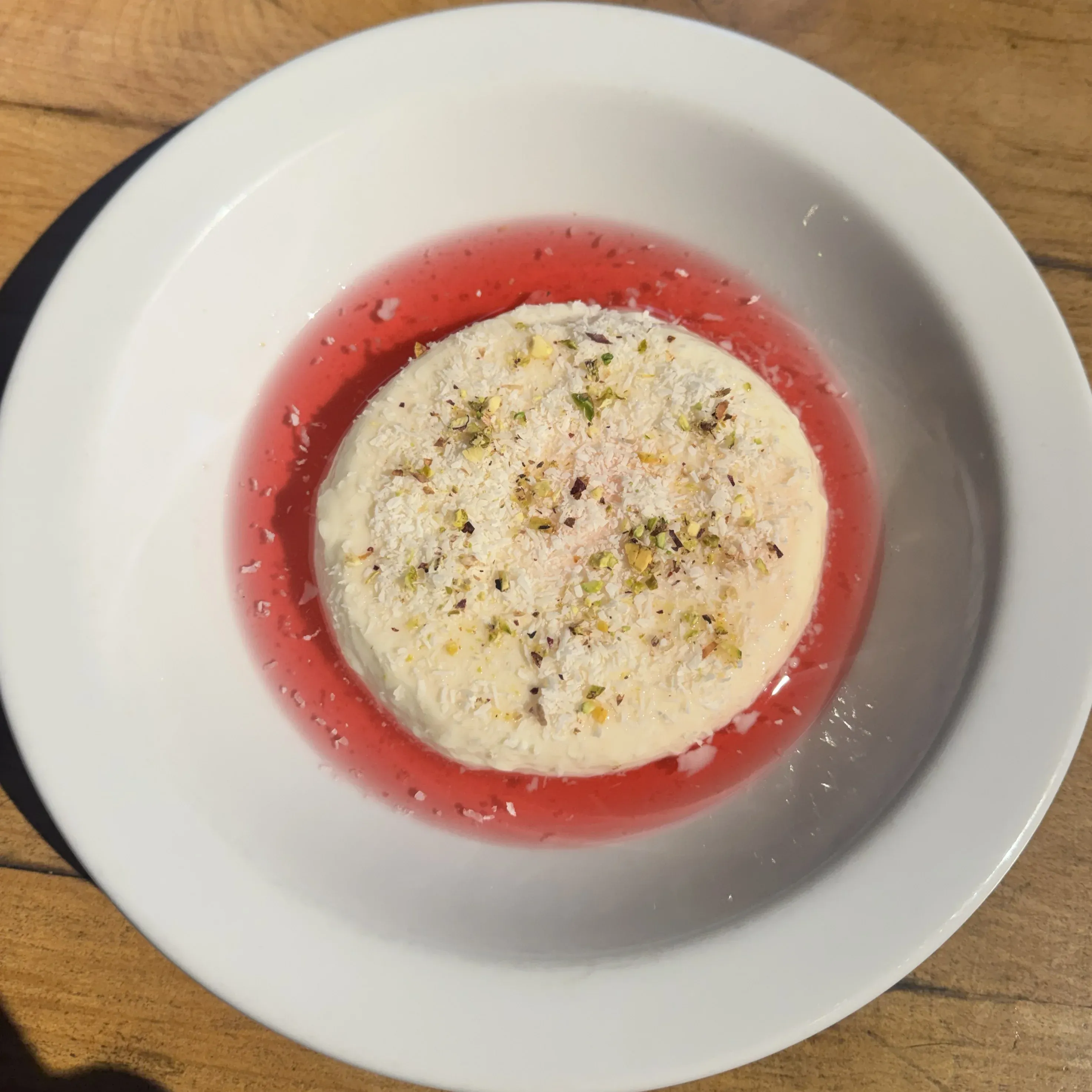 Postre malabi artesanal con almíbar de rosas, hibiscus, coco rallado y pistachos picados
